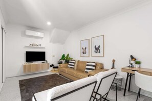 Un salon moderne avec un canapé, un téléviseur, un bureau et une chaise.