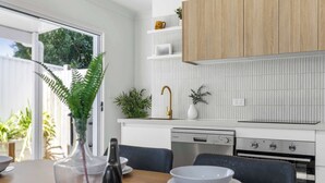 Une cuisine moderne avec des meubles blancs, un lave-vaisselle intégré et une cuisinière à gaz.