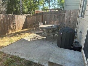 A backyard patio with a table and chairs, a grill, and a wooden fence. - Charming 3-Bedroom Retreat in Hazel Dell, WA – Your Perfect Getaway! (Vancouver)