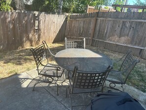 A patio with a round table and four chairs, surrounded by a wooden fence. - Charming 3-Bedroom Retreat in Hazel Dell, WA – Your Perfect Getaway! (Vancouver)