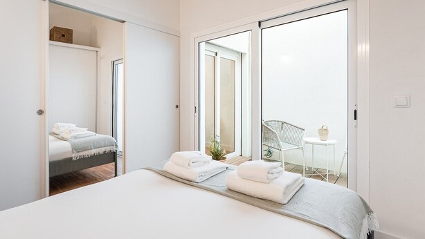 Une chambre moderne avec un lit, une petite table, une chaise et un balcon offrant une vue agréable.