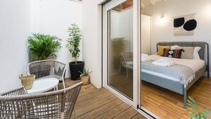 Un balcon avec des fauteuils en osier, une petite table et des plantes en pot.