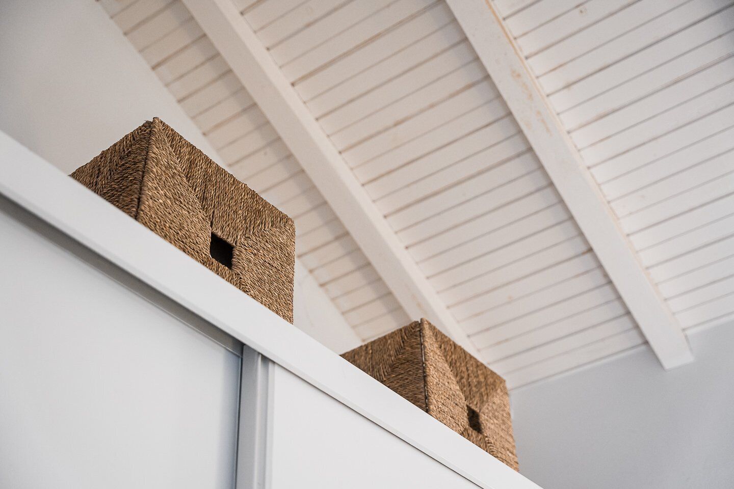 A white ceiling with horizontal lines and two woven baskets on a white ledge.