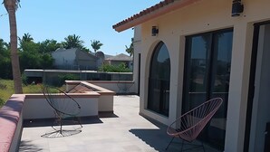 Un patio con suelo de baldosas, una puerta de vidrio y dos sillas.