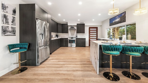 A modern kitchen with dark cabinetry, stainless steel appliances, and a central island with bar stools.