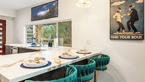 A modern kitchen with a marble countertop, a large window, and a poster on the wall.