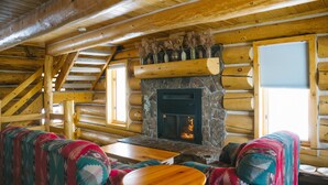 A log cabin interior with a stone fireplace, wooden staircase, and colorful patterned furniture. - Silverthorne Retreat | Pet Friendly + Trail Access (Silverthorne)