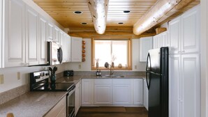 A kitchen with white cabinets, a black refrigerator, and a wooden ceiling. - Silverthorne Retreat | Pet Friendly + Trail Access (Silverthorne)