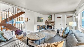 A modern living room with a staircase, a fireplace, and a large sofa. - Lake Tahoe Getaway – Close to Beach & Ski Slopes! (Tahoe City)