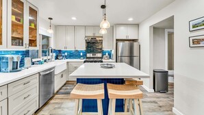 A modern kitchen with white cabinets, a central island, and a blue backsplash. - Lake Tahoe Getaway – Close to Beach & Ski Slopes! (Tahoe City)