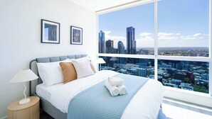 A modern hotel room with a large window, a neatly made bed, and two framed pictures on the wall. - lvl42 2B APT with Free Parking in Melbourne CBD (Melbourne)