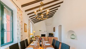 A dining area with a wooden table set for four, surrounded by chairs, and a chandelier overhead. - Mazuecos Rural House  - Beautiful 3 bedroom finca in Sevilla (Lora del Río)