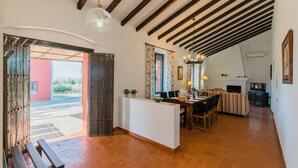 A spacious living area with a wooden ceiling, a dining table, and a fireplace. - Mazuecos Rural House  - Beautiful 3 bedroom finca in Sevilla (Lora del Río)