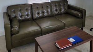 Una sala de estar con un sofá de cuero, una mesa de centro de madera y una ventana con persianas.