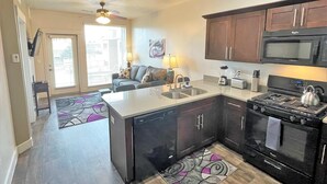 A compact kitchen with a dishwasher, stove, microwave, and a dining area with a table and chairs.