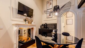 A dining area with a glass table, black chairs, a fireplace, and a modern pendant light.
