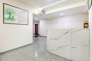 Ein Hotel-Empfangsbereich mit einem Marmor-Empfangstresen, einem gerahmten Informationsplakat und einem Gang zu einem weiteren Raum.