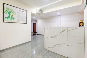 Zona de recepción de hotel con un mostrador de mármol, un cartel informativo enmarcado y un pasillo que conduce a otra habitación.