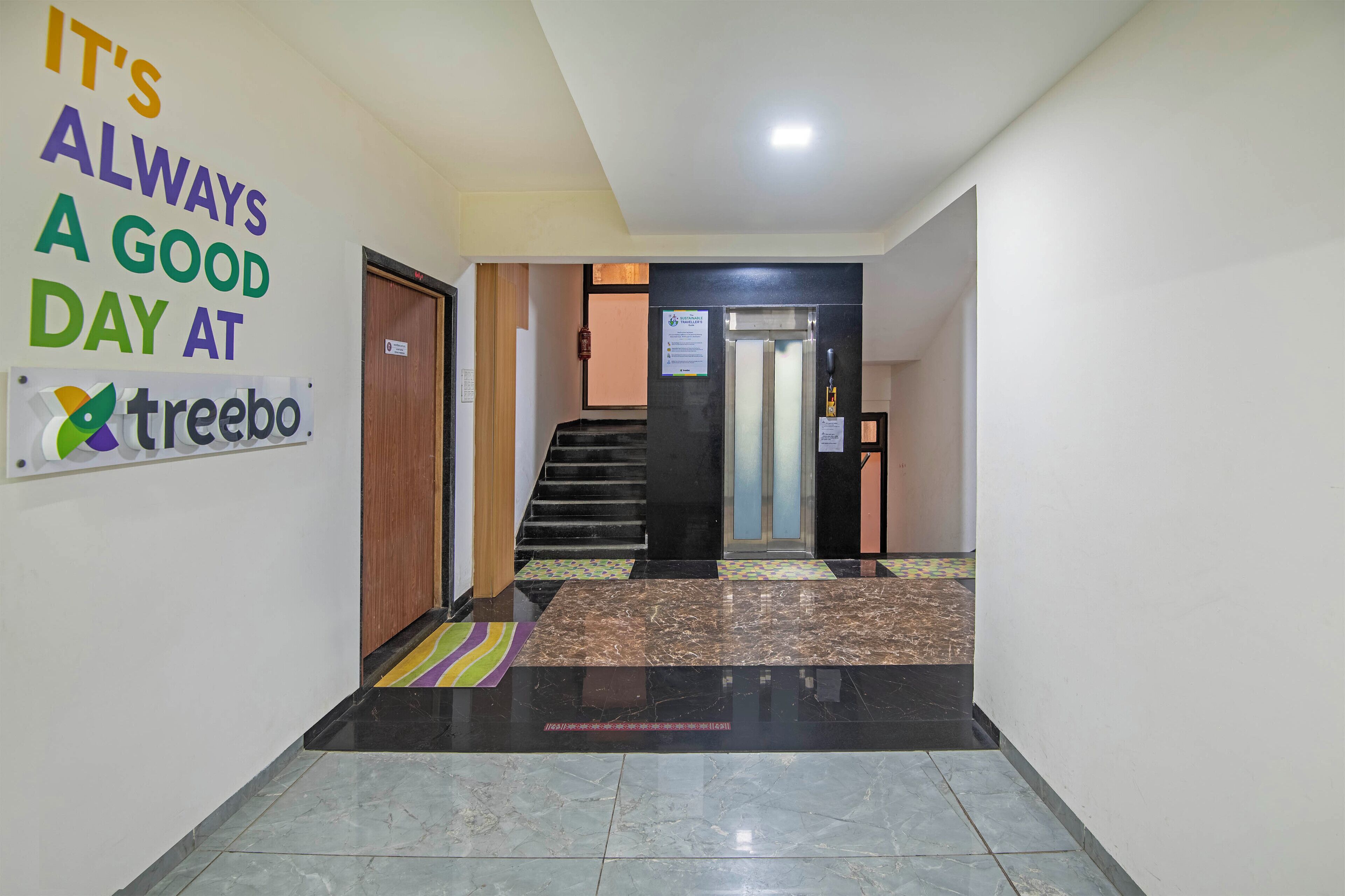 Un vestíbulo de hotel con piso de mármol, una escalera y un letrero que dice 'It's always a good day at treebo'.