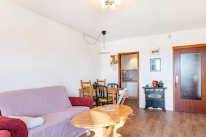 Una sala de estar con un sofá, una mesa de madera y una zona de cocina con un armario y una puerta.