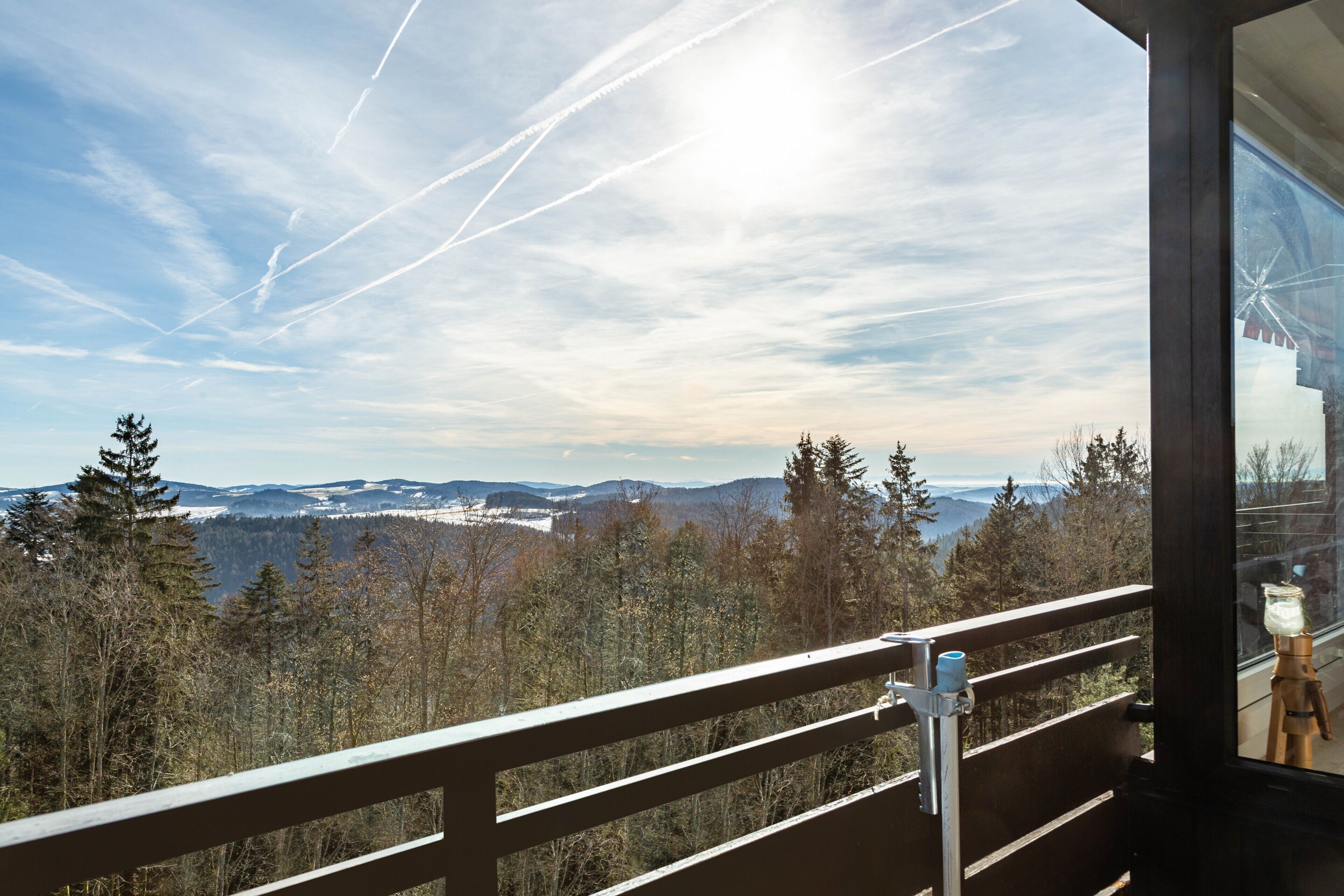 Ein Balkon mit Blick auf eine bewaldete Landschaft und ferne Berge.