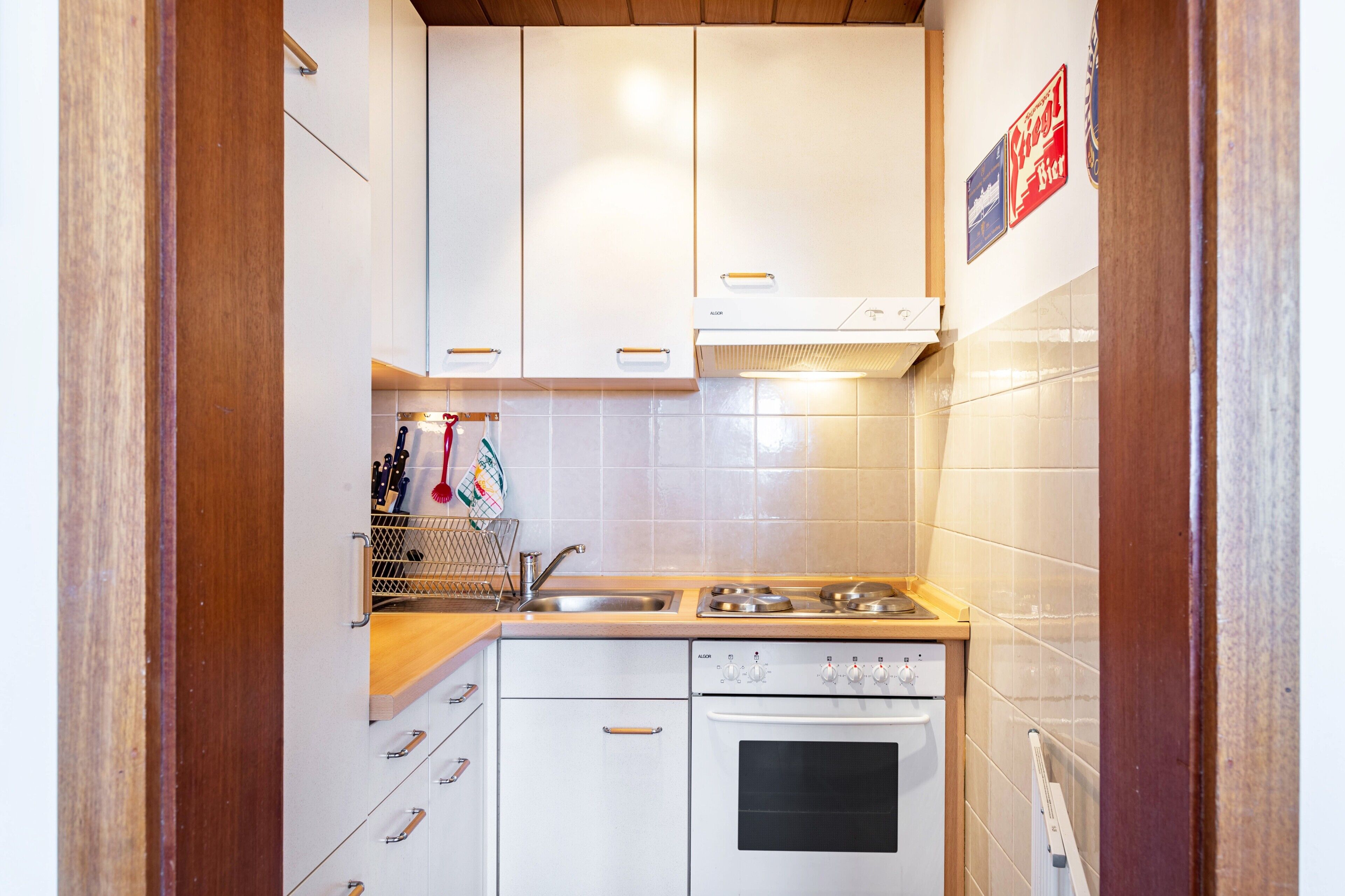 A compact kitchen with white cabinets, a stove, an oven, and a sink.