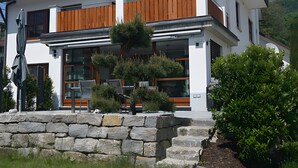 Een modern huis met twee verdiepingen, een stenen fundering, grote ramen en een houten balkon.