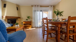 A dining area with a wooden table and chairs, a fireplace, and a view through a glass door. - Vacation home Golfa by Interhome (Deltebre)