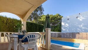 An outdoor patio with a pool, white plastic chairs, and a table set for dining. - Vacation home Golfa by Interhome (Deltebre)