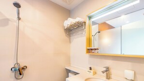 Un baño moderno con ducha, lavamanos y espejo.