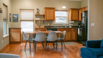 A modern kitchen with wooden cabinets, a dining table with chairs, and a refrigerator.