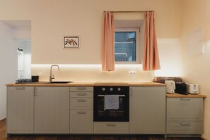 Uma cozinha compacta com pia, forno e janela com cortinas.