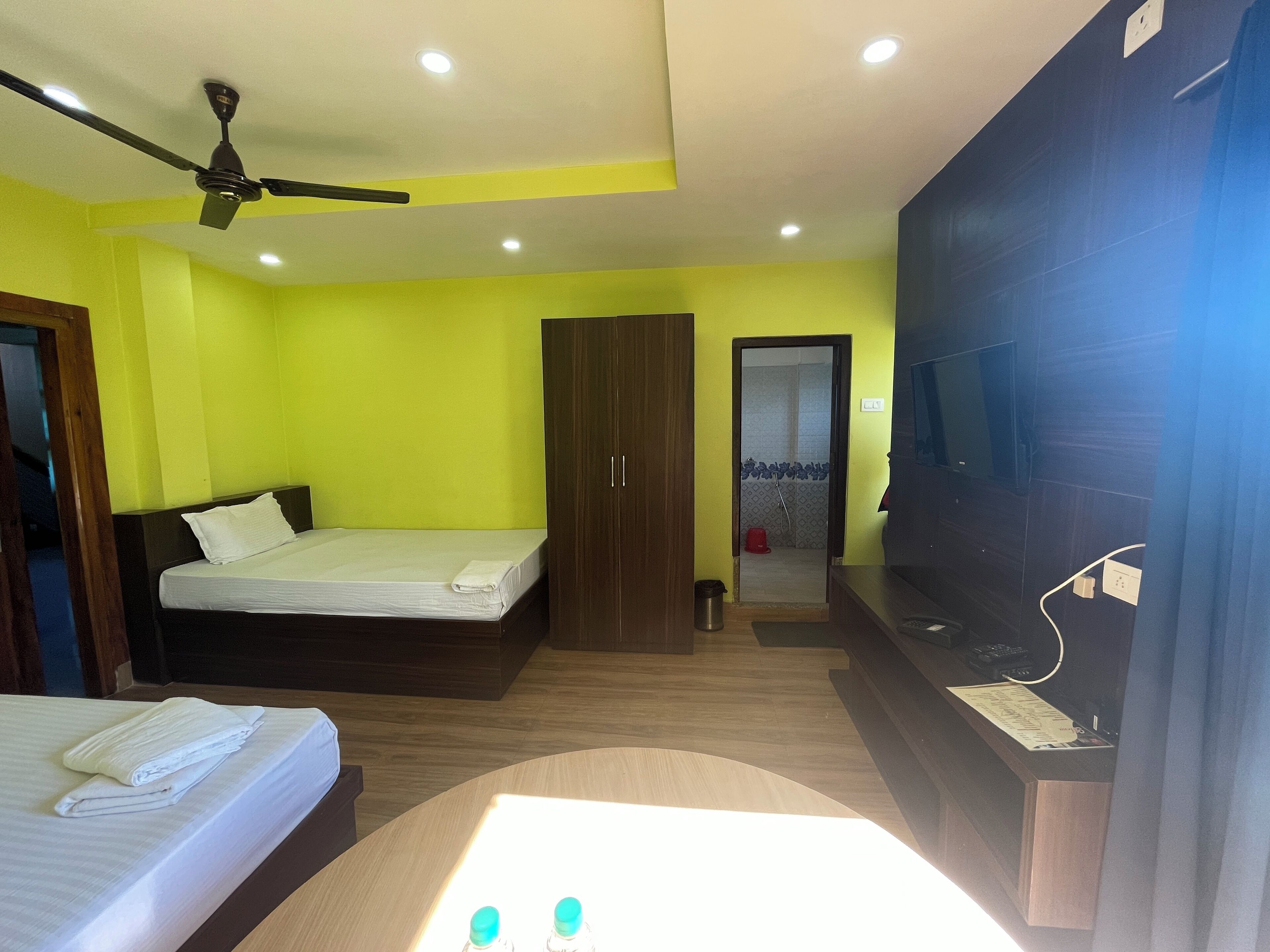 A hotel room with a bed, a desk, a wardrobe, a shower area, and a television.