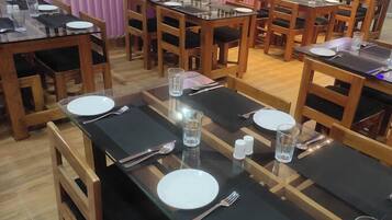 A dining area with multiple tables set for guests, each with plates, cutlery, and glasses.