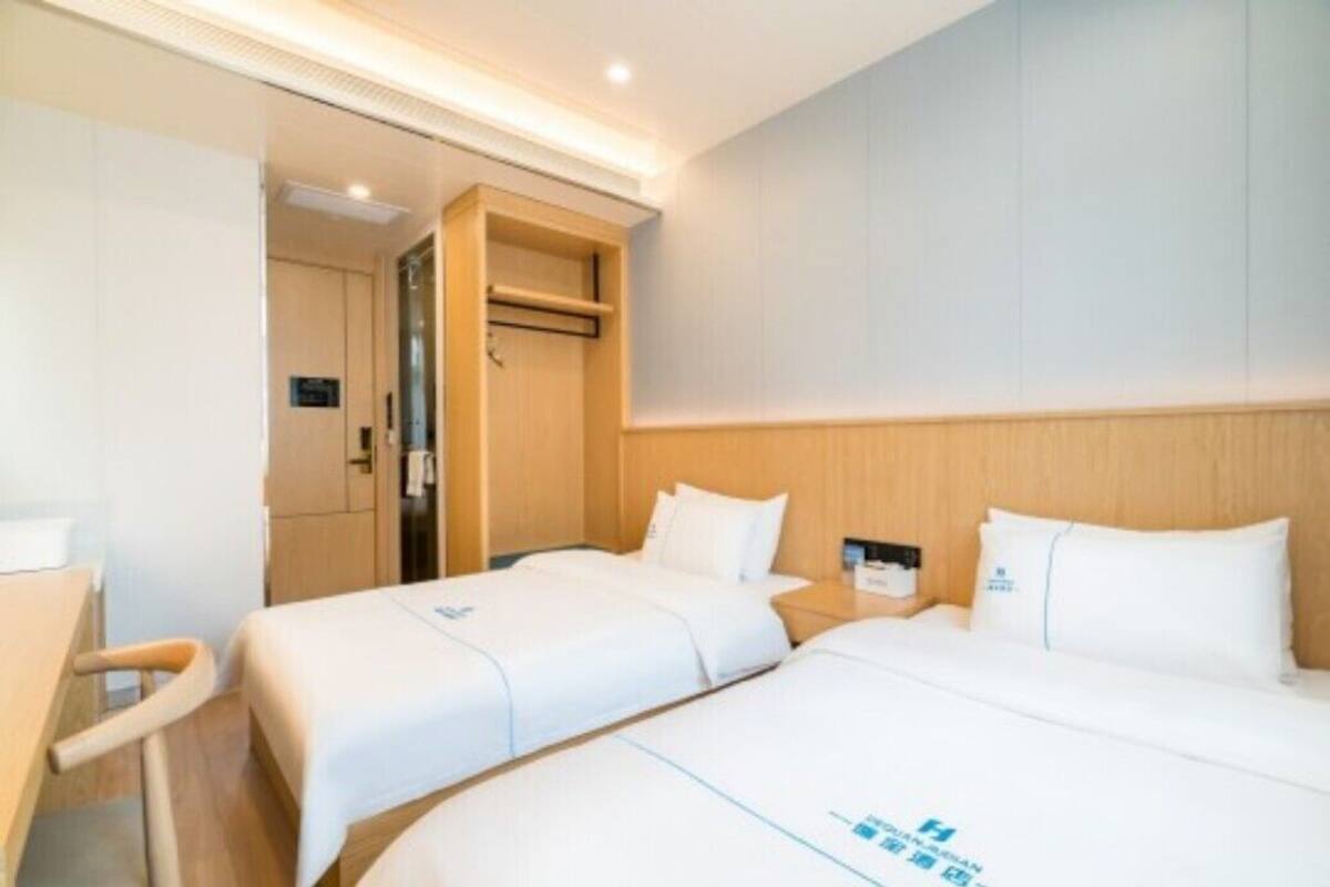 Una habitación de hotel con dos camas, un armario de madera y un escritorio pequeño con una silla.