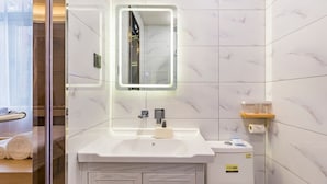 Un baño moderno con un lavamanos, espejo y retrete blancos.