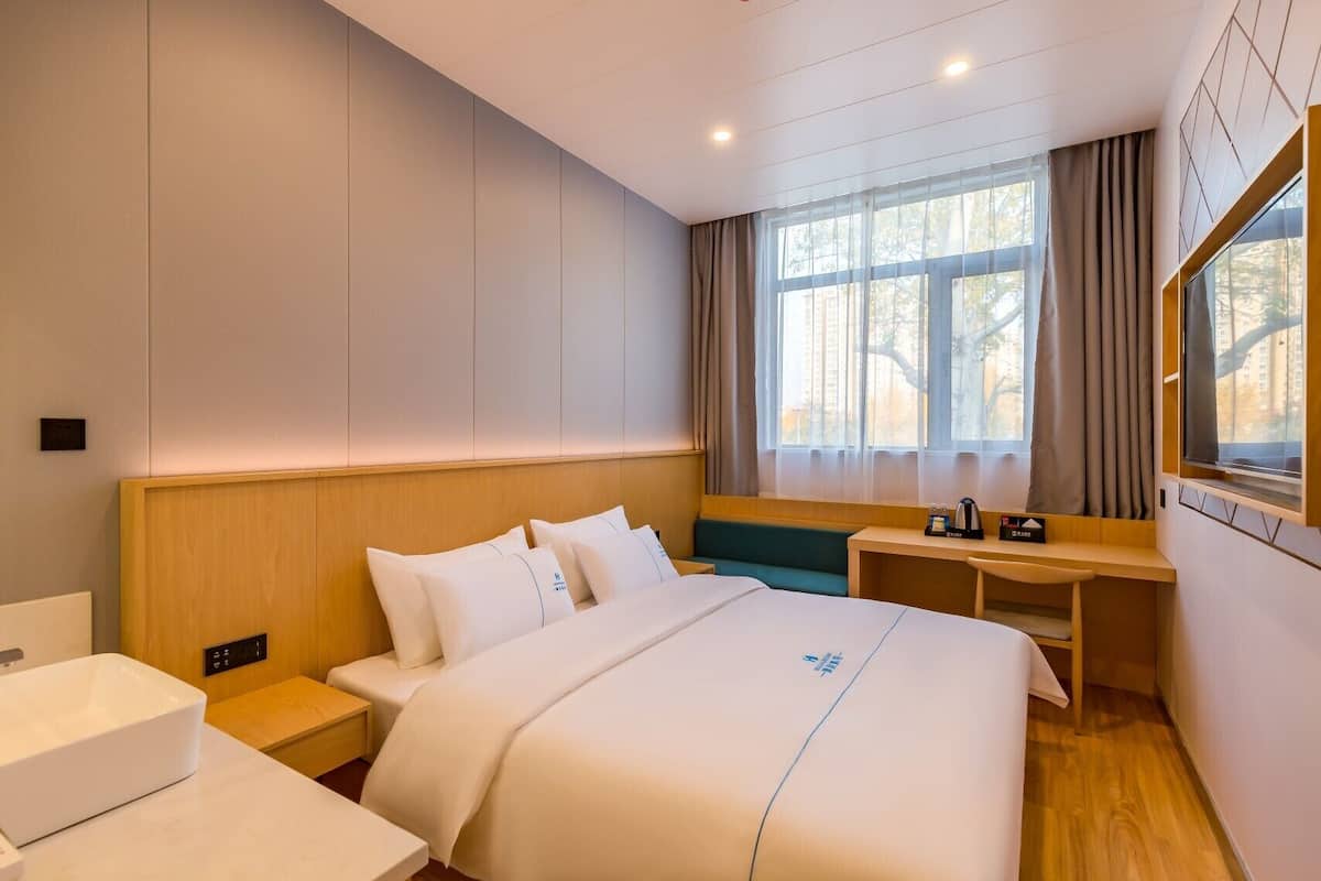 Una habitación de hotel con cama, mesita de noche y escritorio con silla.