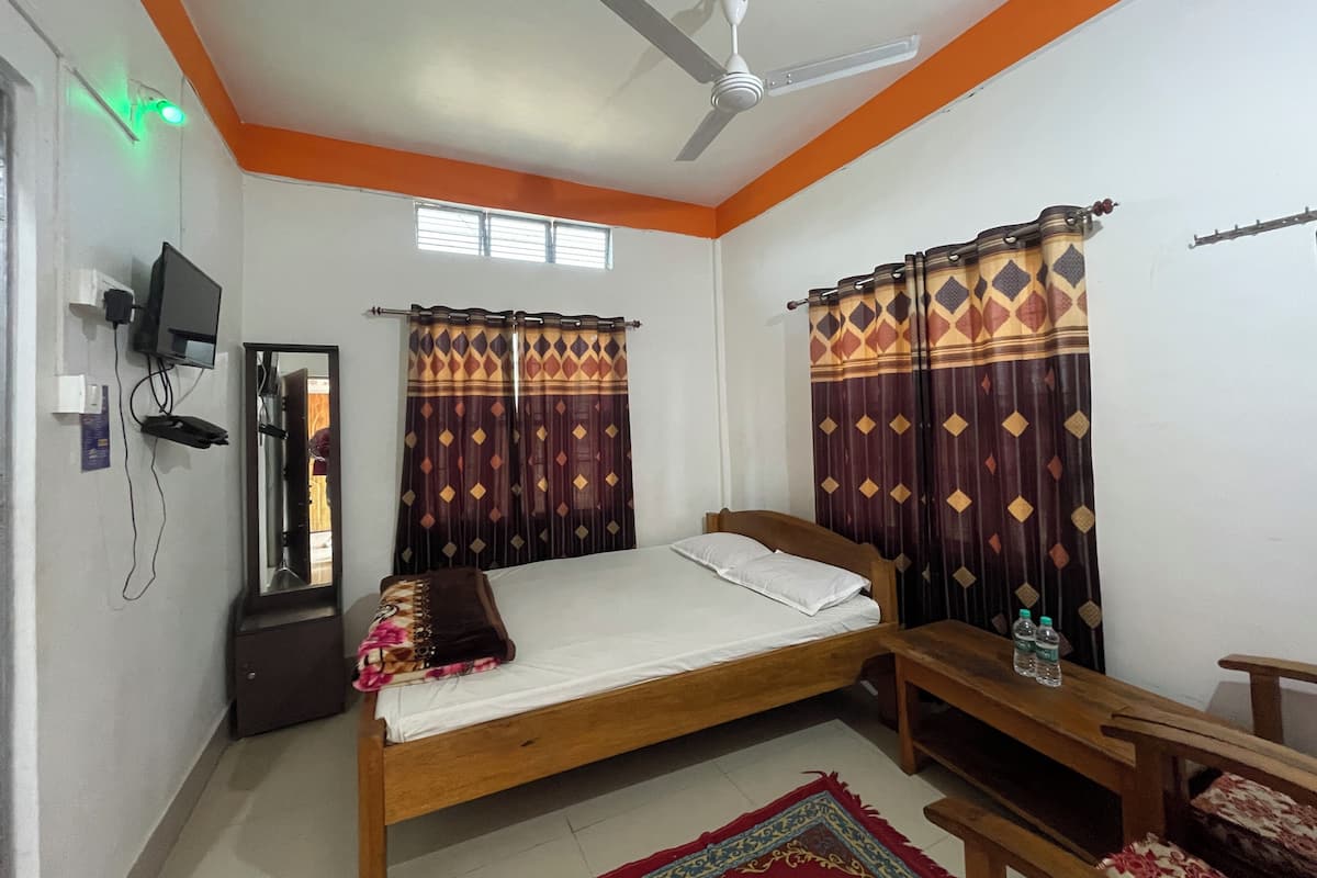 A bedroom with a bed, a desk, a chair, a ceiling fan, and curtains.
