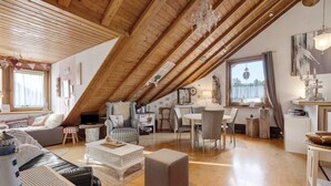 A cozy loft-style room with a sloped ceiling, a dining area, and a seating area with a fireplace.