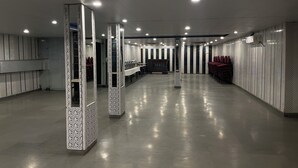 Amplio espacio interior, bien iluminado, con una larga barra y sillas, probablemente un área de espera o de atención al cliente.