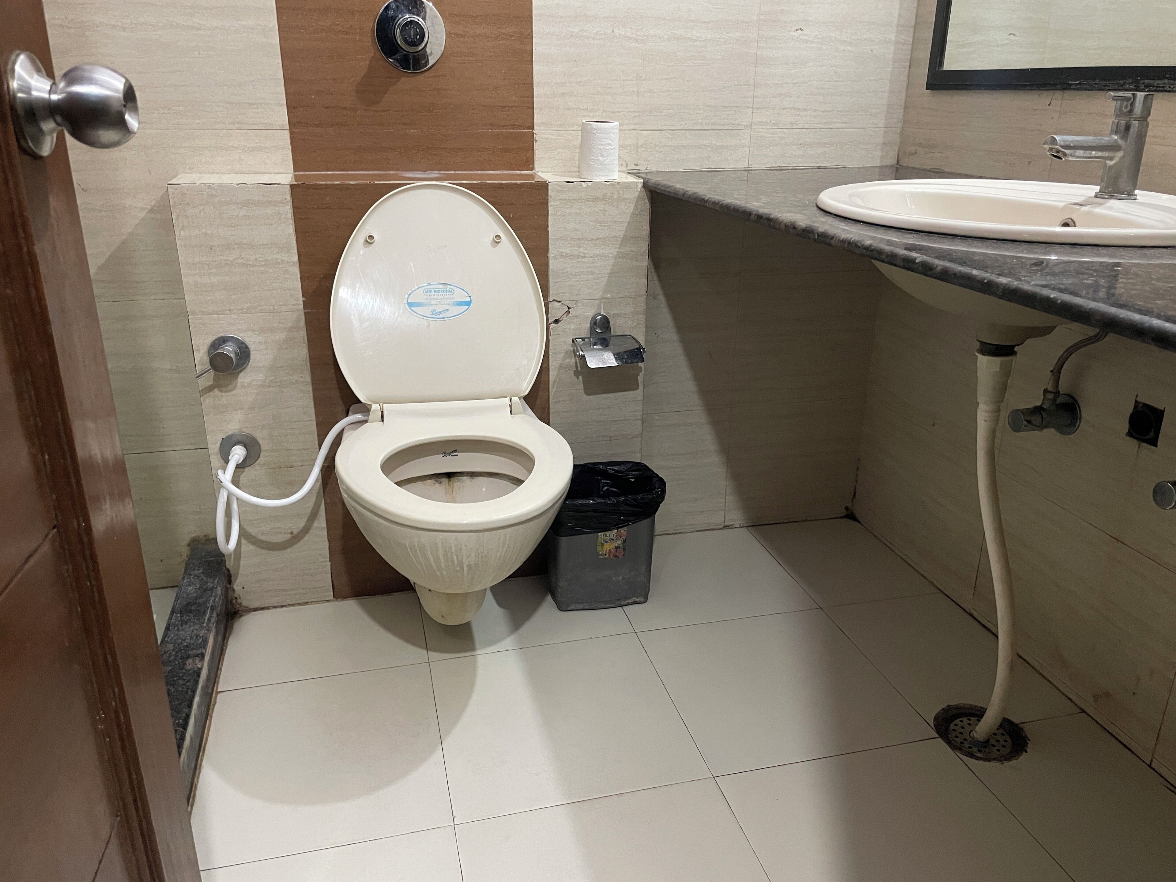 A bathroom with a toilet, a sink, and a trash bin.
