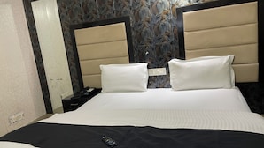 Una habitación de hotel con cama, mesita de noche, teléfono e enchufe.