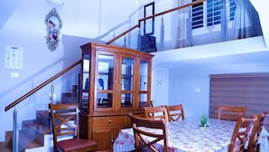A dining area with a wooden cabinet and a table set for four. - Aanvis Inn boutique home stay (Ootacamund)