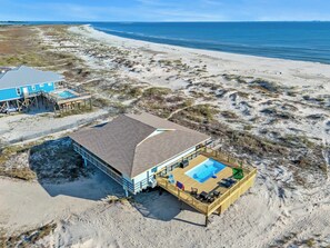 A beachside property with a large house, a pool, and a pier.