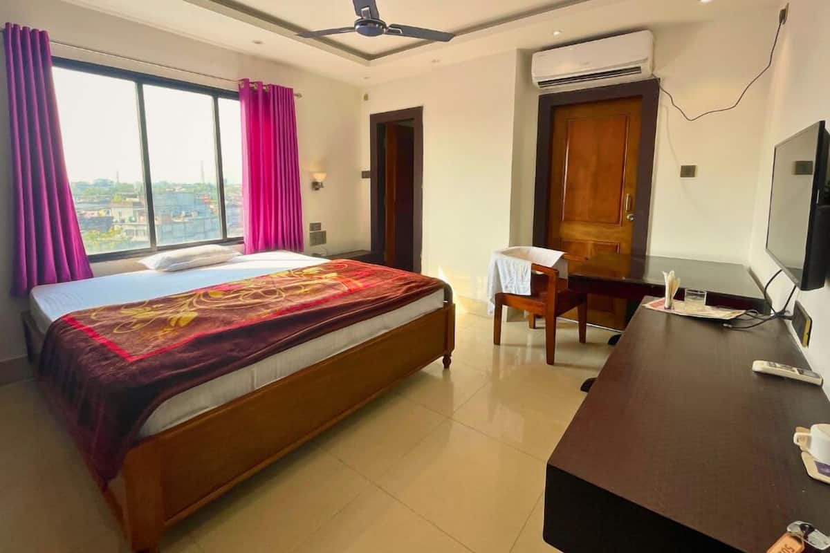 Une chambre d’hôtel équipée d’un lit, d’un bureau, d’une télévision et d’un appareil de climatisation.