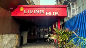 Eine rote Markise mit dem Schriftzug "LIVING HUB" über einer Tür.