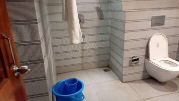Un baño con paredes a rayas, un inodoro blanco, un cubo azul y una toalla colgada en la pared.
