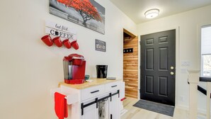 Una cocina con espacio para café, una puerta negra y una pared de madera.