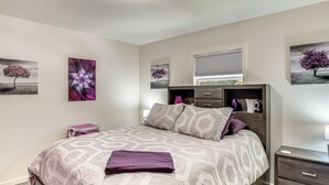 Un dormitorio con cama, mesita de noche, cómoda y decoración en la pared.
