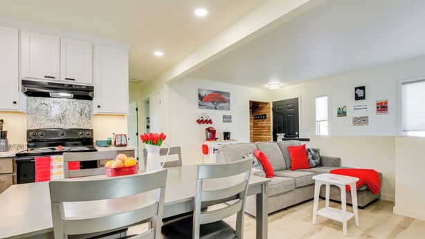 Una cocina moderna con armarios blancos, estufa integrada y un comedor con mesa y sillas.